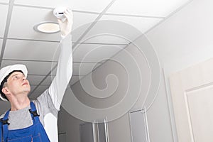 A worker installs a fire safety sensor photo