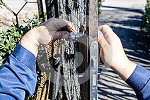worker installs new door lock in iron gate closeup