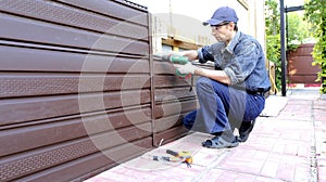 Worker installs plastic siding on the facade photo