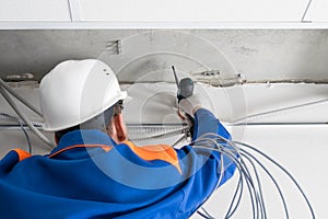 A worker installs a router on the wall to transmit the Internet signal in offices and homes, rear view