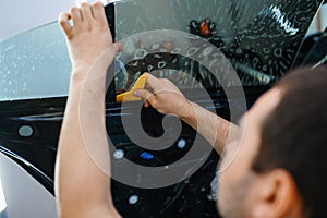 Worker installs wetted car tinting, tuning service