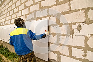 The worker insulates the house from foam plastic