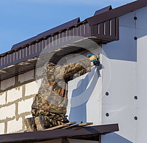 Worker insulates the walls of the house with plastic panels