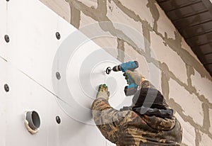 Worker insulates the walls of the house with plastic panels