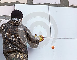 Worker insulates the walls of the house with plastic panels