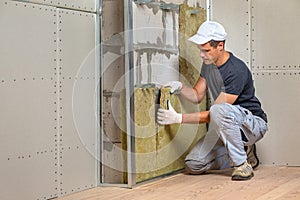 Worker insulating a room wall with mineral rock wool thermal insulation