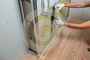 Worker insulating a room wall with mineral rock wool thermal insulation