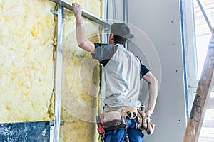 Worker insulating wall of a new building on construction site