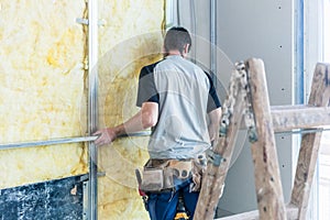 Worker insulating wall of a new building on construction site