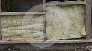 Worker insulating wooden house frame with rock-wool