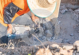 A worker with a jackhammer breaks concrete pilesl