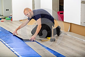 Worker joining click lock vinyl floor plank covering at home renovation. Man laying PVC-floor.