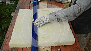 Worker knife cutting rockwool for house insulation