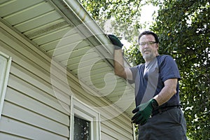 Worker On Ladder Getting Ready To Clean Gutters