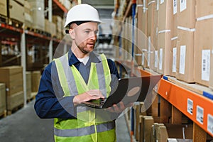 Worker with laptop computer in mail order warehouse