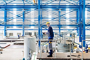 Worker in large metal workshop checking work