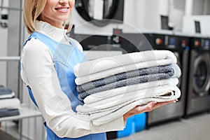 Worker Laundry girl holding fresh towels in her hands and smiles