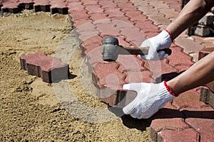 A worker laying concrete paving blocks.