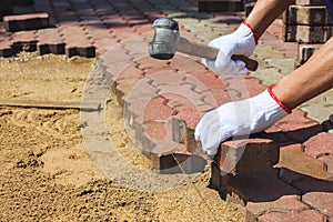 Worker laying concrete paving blocks.