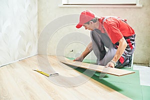 Worker laying laminate floor covering at home renovation