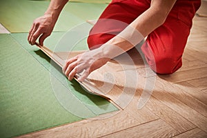 Worker laying laminate floor covering at home renovation