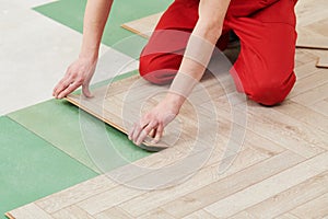 Worker laying laminate floor covering at home renovation