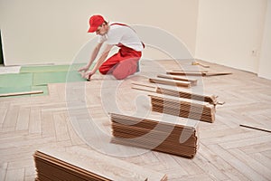 worker laying laminate floor covering at home renovation