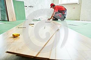 worker laying laminate floor covering at home renovation