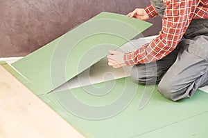 Worker laying laminate floor underlayer padding