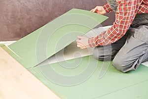 Worker laying laminate floor underlayer padding photo