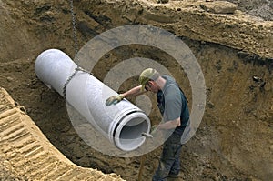 Worker laying new sewer pipe in slot in the street