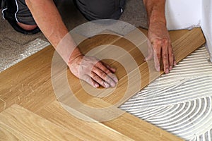 Worker laying parquet flooring.