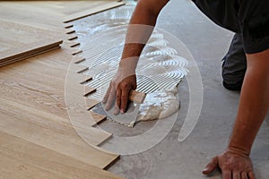 Worker laying parquet flooring and installing wooden laminate