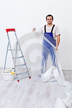 Worker laying protection film before painting