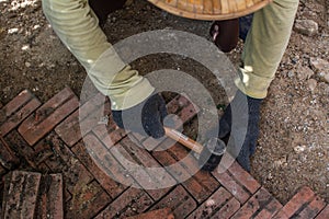 worker laying red brick pathway around the house