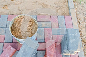 Worker laying red and gray concrete paving blocks. Road Paving, construction