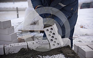 A worker lays cement on a concrete brick, the construction of an apartment building.