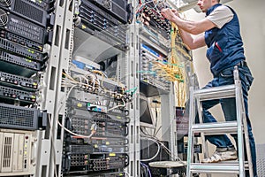 Worker lays communication cables. Technological concept.Technician standing on a ladder connects internet wires. The specialist