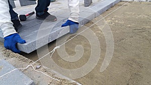 A worker lays paving slabs with a rubber mallet under stretched twine - 12s