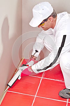 Worker lays silicone gun sealant photo