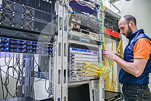 Worker lays telecommunication cables in the server room. A man twists the wires in a modern data center. A technician connects