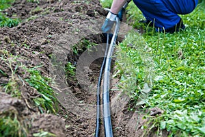 Worker lays a water pipe into the ground