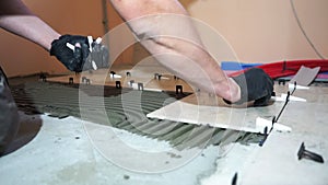 A worker is leveling the ceramic tile with wedges and clips. Tile leveling system