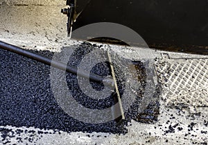 Worker leveling fresh asphalt