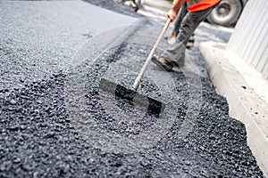 Worker leveling fresh asphalt on a road construction site photo