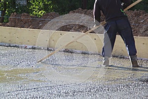 worker leveling fresh concrete slab with a special wooden workin