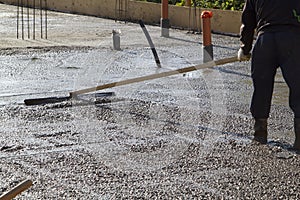 worker leveling fresh concrete slab with a special wooden workin