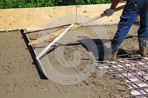 worker leveling fresh concrete slab with special working tool