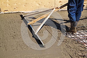 worker leveling fresh concrete slab with special working tool