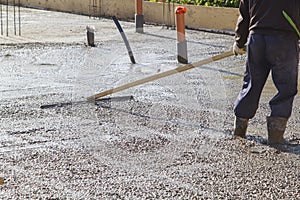 worker leveling fresh concrete slab with a special working tool